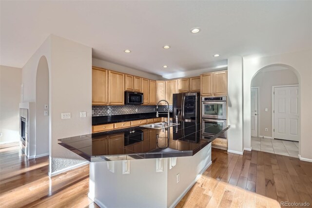 2660 Timberchase Trl, Highlands Ranch, CO 80126 - kitchen with appliances with stainless steel finishes, a sink, light brown cabinetry, arched walkways, and recessed lighting