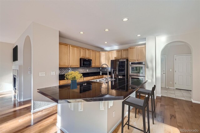 2660 Timberchase Trl, Highlands Ranch, CO 80126 - kitchen with appliances with stainless steel finishes, a sink, arched walkways, light brown cabinets, and recessed lighting