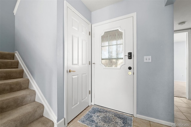 entryway featuring stairway, light tile patterned flooring, and baseboards