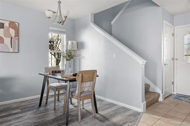 dining room featuring tile patterned flooring, stairway, baseboards, and an inviting chandelier