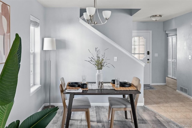 dining space featuring baseboards, visible vents, a notable chandelier, and light tile patterned flooring