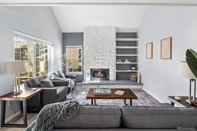 living room with vaulted ceiling, a stone fireplace, wood finished floors, and baseboards