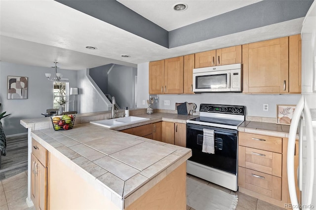 kitchen featuring tile countertops, white microwave, light tile patterned flooring, a sink, and range with electric cooktop