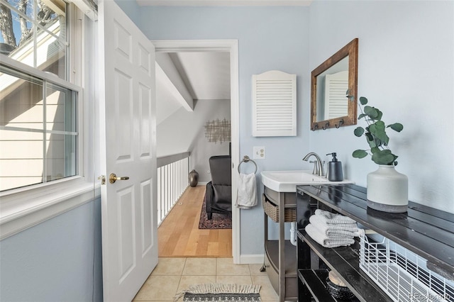 bathroom with vaulted ceiling with beams, tile patterned flooring, a sink, and baseboards