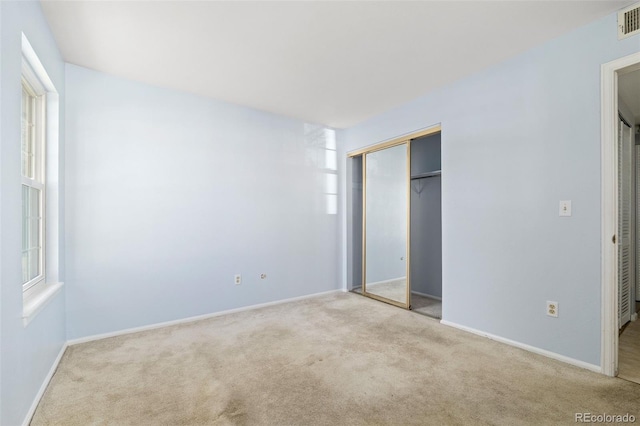 unfurnished bedroom featuring carpet, a closet, multiple windows, and baseboards