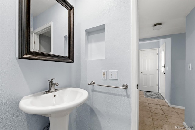 bathroom with tile patterned flooring, a sink, and baseboards