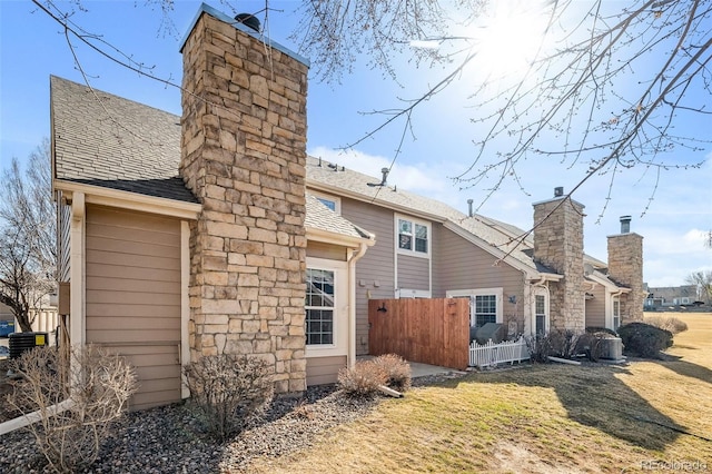 back of property featuring a shingled roof, a chimney, and fence