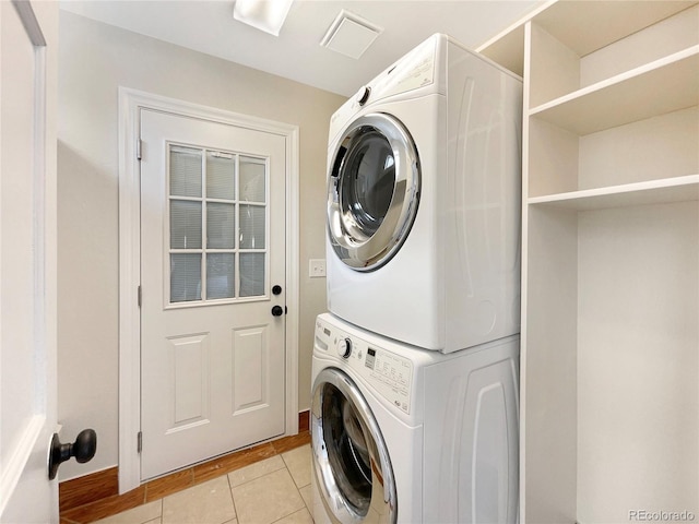 laundry room with light tile flooring and stacked washer / drying machine