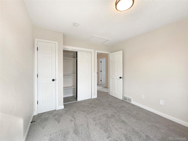 unfurnished bedroom featuring a closet, dark carpet, and a textured ceiling