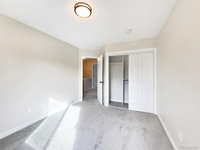 unfurnished bedroom with a textured ceiling, light carpet, and a closet