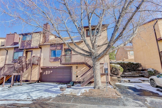 townhome / multi-family property with a garage, stairs, concrete driveway, stucco siding, and a chimney