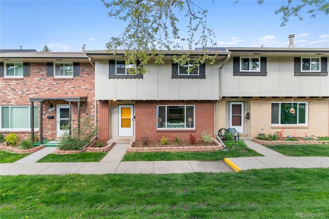 12708 W Virginia Ave, Lakewood, CO 80228 - townhome / multi-family property featuring a front lawn, brick siding, and board and batten siding