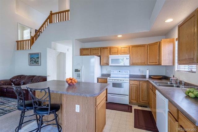 kitchen featuring white appliances, a breakfast bar area, a kitchen island, and sink