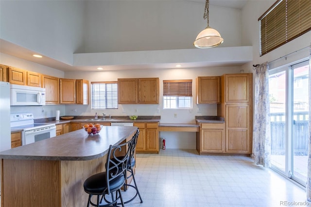 kitchen featuring pendant lighting, sink, white appliances, high vaulted ceiling, and a center island