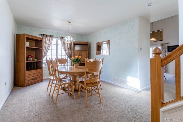 carpeted dining area featuring an inviting chandelier