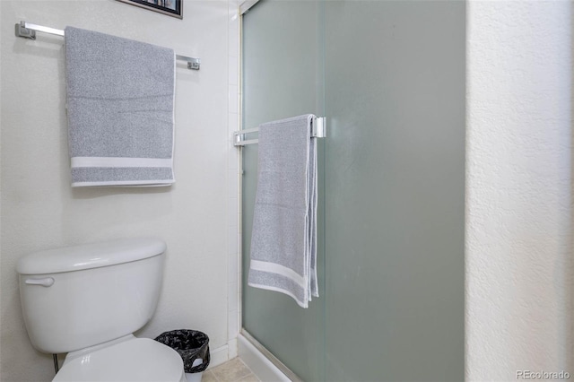 bathroom featuring a shower with door and toilet