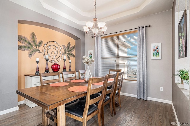 dining room featuring a tray ceiling, dark hardwood / wood-style flooring, and a notable chandelier