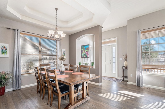 dining area featuring a tray ceiling, dark hardwood / wood-style floors, and a chandelier