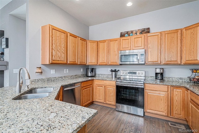 kitchen with stainless steel appliances, light stone countertops, and sink