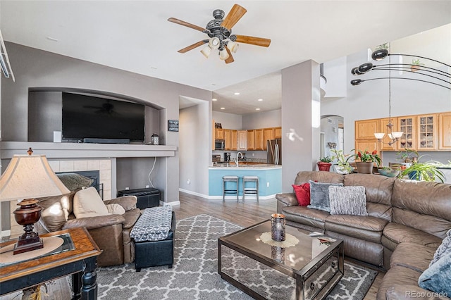 living room with hardwood / wood-style floors, sink, ceiling fan with notable chandelier, and a fireplace