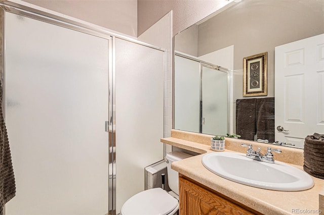 bathroom with vanity, a shower with shower door, and toilet