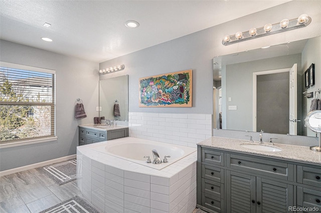 bathroom featuring vanity and tiled tub