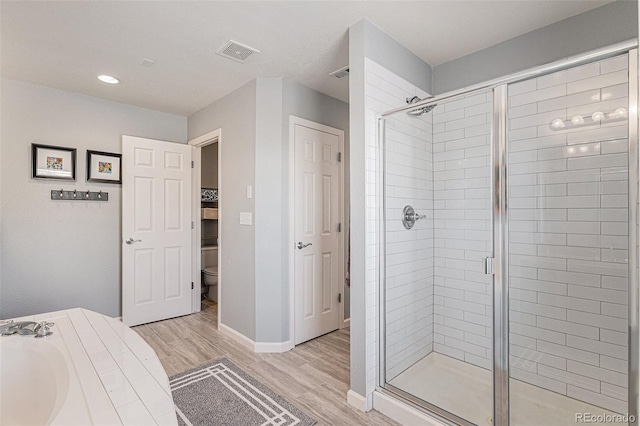 bathroom with hardwood / wood-style flooring, toilet, and separate shower and tub