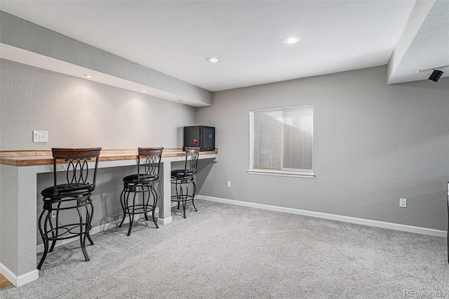 kitchen with a kitchen bar, kitchen peninsula, wooden counters, and carpet