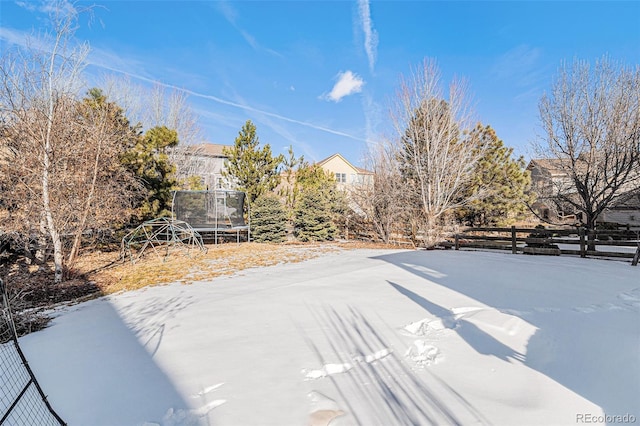 yard layered in snow featuring a trampoline