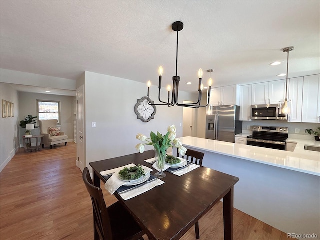 dining room featuring sink, wood-type flooring, and an inviting chandelier