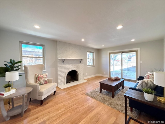 living room with a wealth of natural light, a fireplace, and light hardwood / wood-style floors