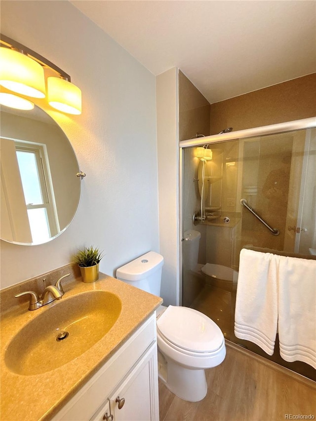 bathroom featuring hardwood / wood-style floors, vanity, a shower with door, and toilet