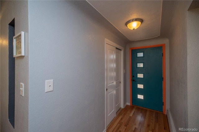 interior space featuring a baseboard radiator, baseboards, and wood finished floors