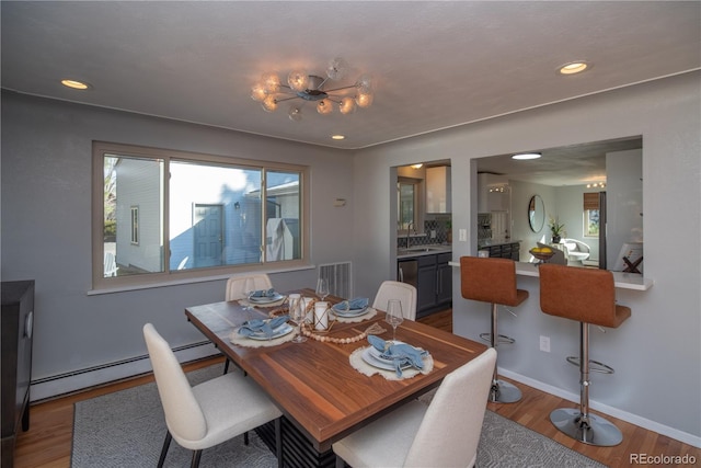 dining room featuring wood finished floors, visible vents, baseboards, recessed lighting, and a baseboard heating unit