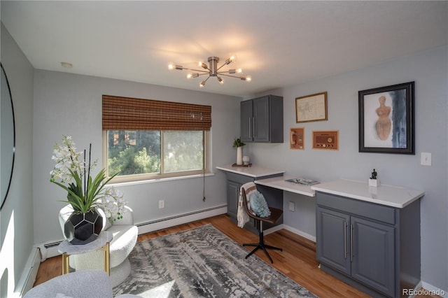 home office with light wood finished floors, a chandelier, built in study area, and a baseboard heating unit