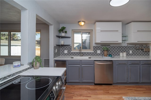 kitchen featuring a sink, open shelves, light countertops, and stainless steel appliances