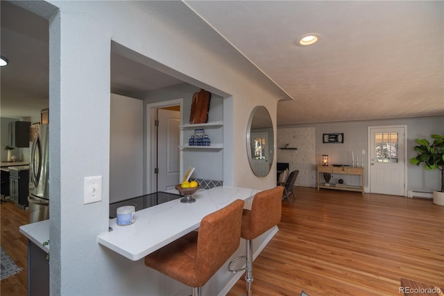 dining space featuring recessed lighting, a large fireplace, and light wood finished floors