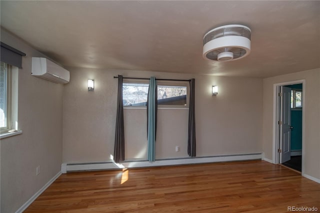 empty room featuring baseboard heating, an AC wall unit, baseboards, and wood finished floors