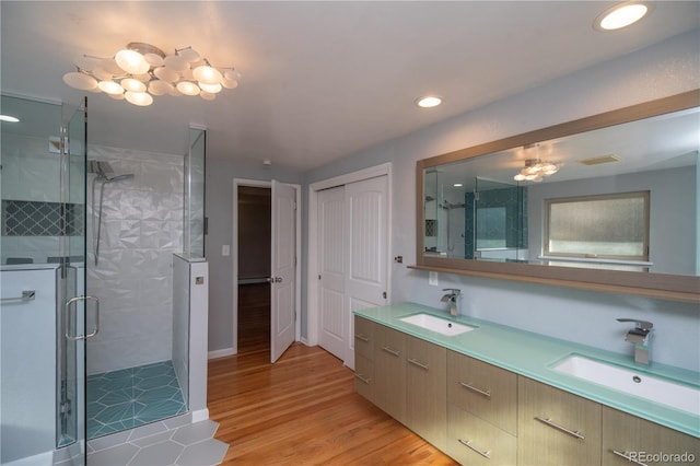 full bath featuring a stall shower, wood finished floors, and a sink