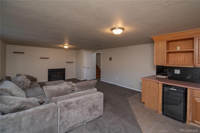 living area featuring wine cooler, a glass covered fireplace, a textured ceiling, and stairs