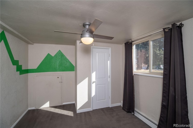 interior space with a baseboard radiator, baseboards, carpet, and a textured wall