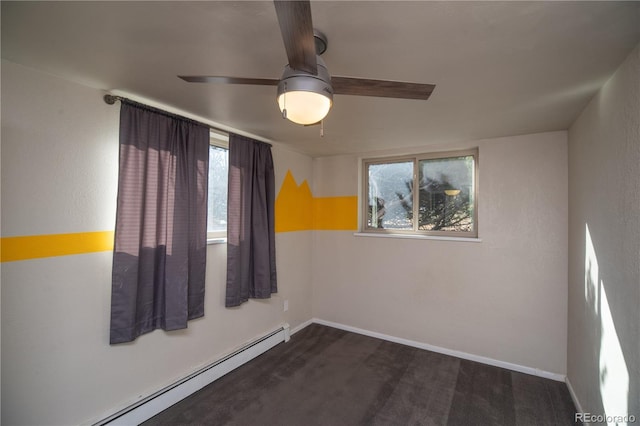 spare room with dark colored carpet, a baseboard heating unit, baseboards, and ceiling fan