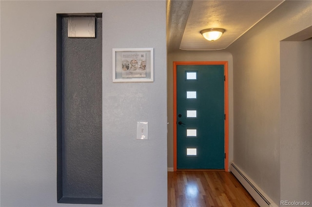 doorway to outside featuring wood finished floors and baseboard heating