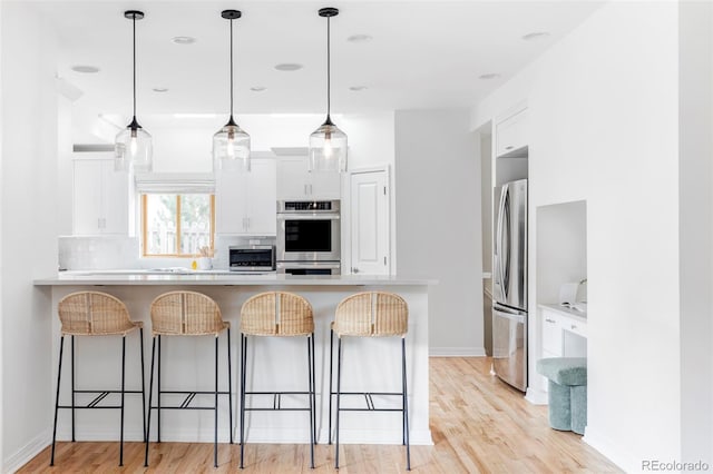 1272 S Milwaukee St, Denver, CO 80210 - kitchen with appliances with stainless steel finishes, a kitchen bar, white cabinets, and light countertops
