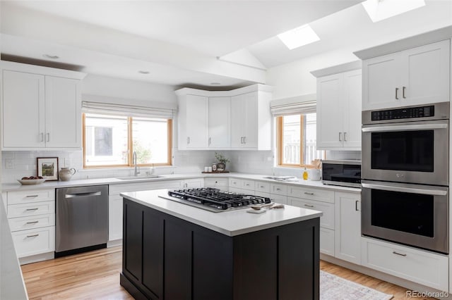1272 S Milwaukee St, Denver, CO 80210 - kitchen with stainless steel appliances, white cabinets, light countertops, backsplash, and lofted ceiling