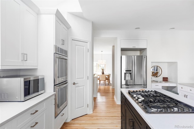 1272 S Milwaukee St, Denver, CO 80210 - kitchen featuring appliances with stainless steel finishes, light countertops, light wood finished floors, white cabinets, and recessed lighting