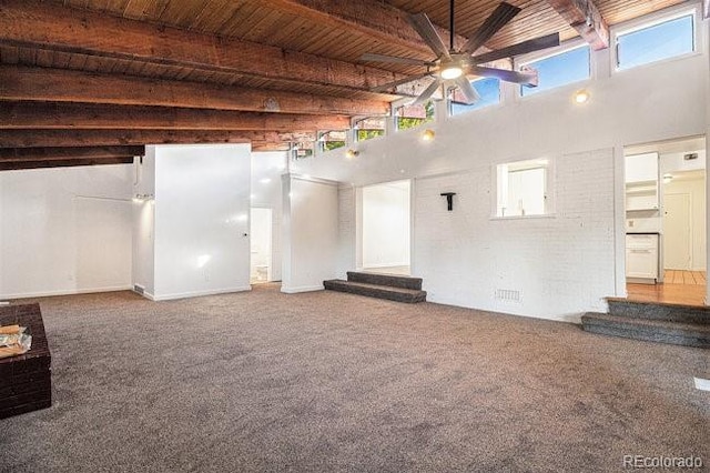 unfurnished living room featuring carpet flooring, beam ceiling, wood ceiling, and a towering ceiling