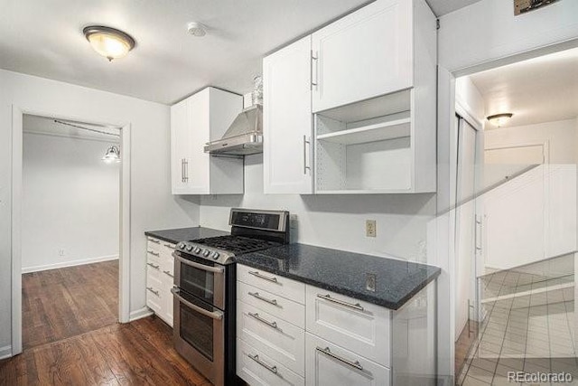 kitchen featuring white cabinetry, wall chimney exhaust hood, dark hardwood / wood-style floors, dark stone countertops, and range with two ovens