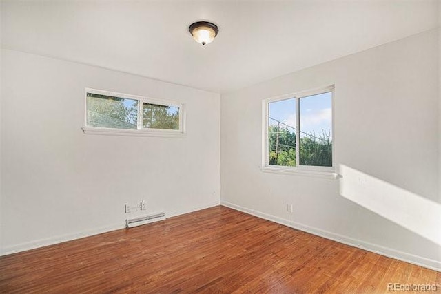 unfurnished room with wood-type flooring and a baseboard heating unit