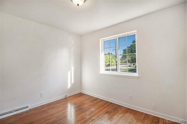 unfurnished room with hardwood / wood-style flooring and baseboard heating